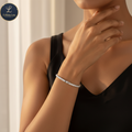 Woman wearing a bracelet with a neutral background, featuring the brand FrillsbyLam
