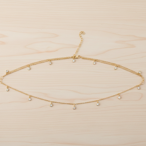 Gold necklace with small beads on a light wood background